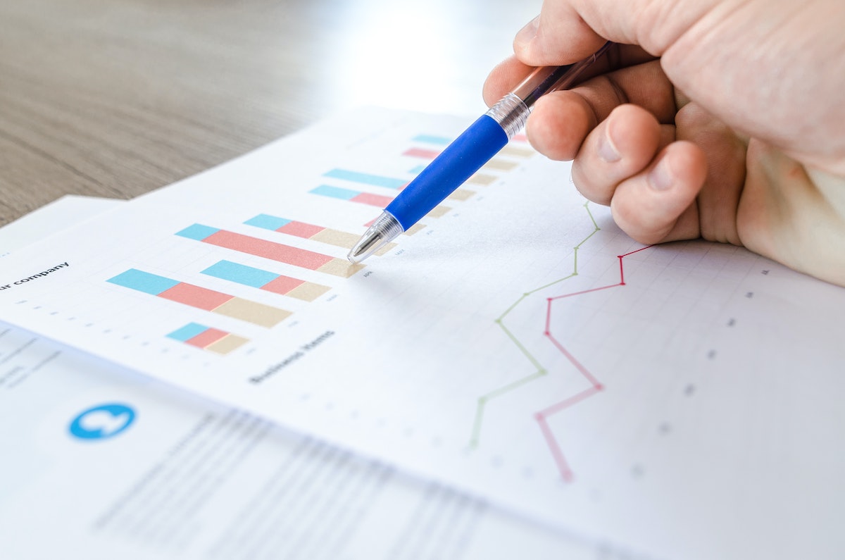 person holding pen against chart printout